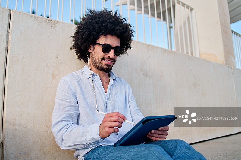 年轻男子在户外用手写笔在平板上绘画图片素材