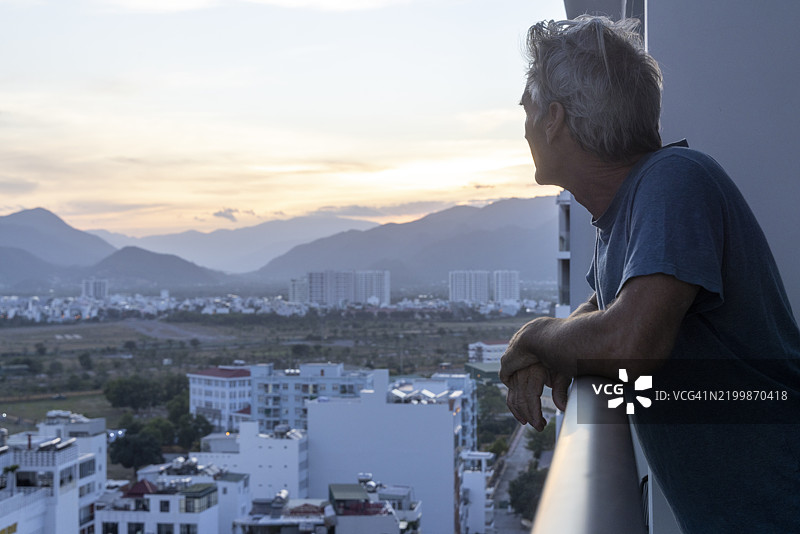 成熟男性在城市上方的阳台上享受日出图片素材