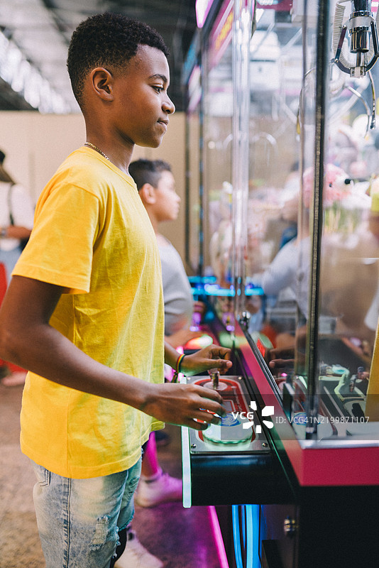少年男孩在游戏厅玩抓娃娃机图片素材