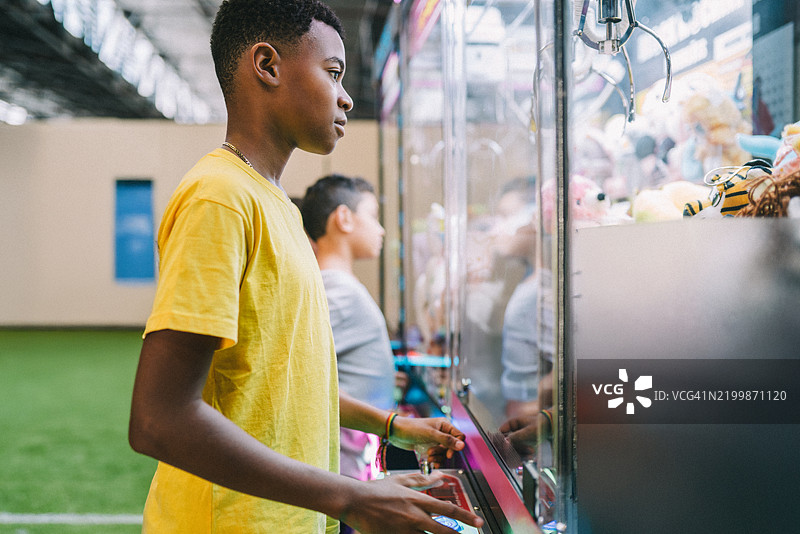 少年男孩在游戏厅玩抓娃娃机图片素材