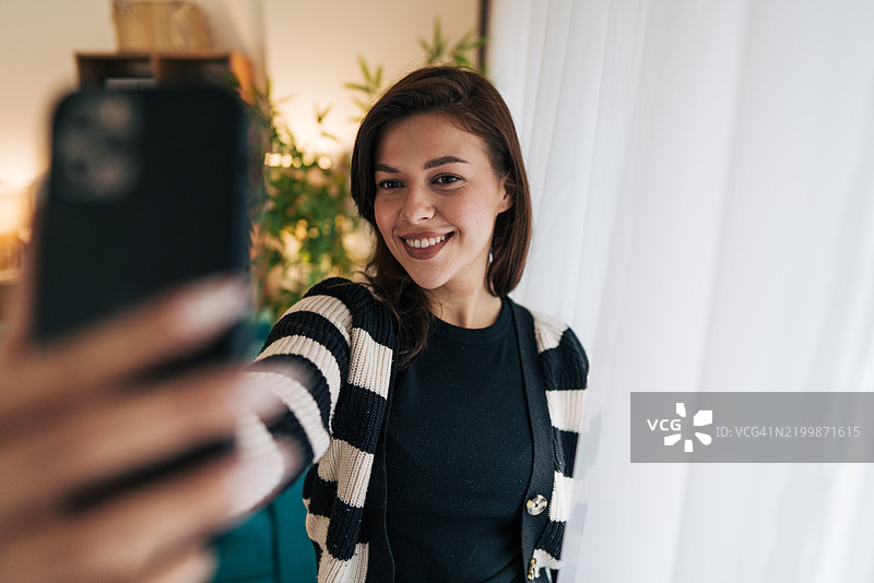 年轻女性在家用智能手机自拍图片素材