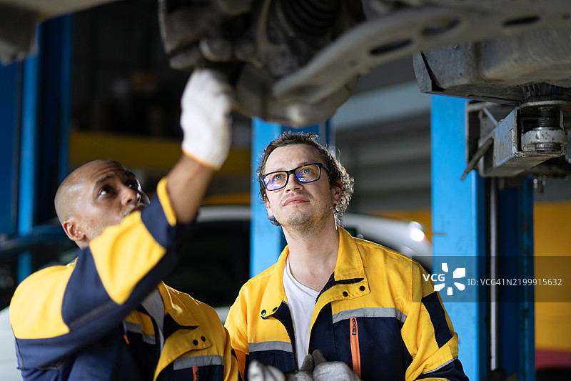 蓝领工人在汽车维修车间工作。图片素材