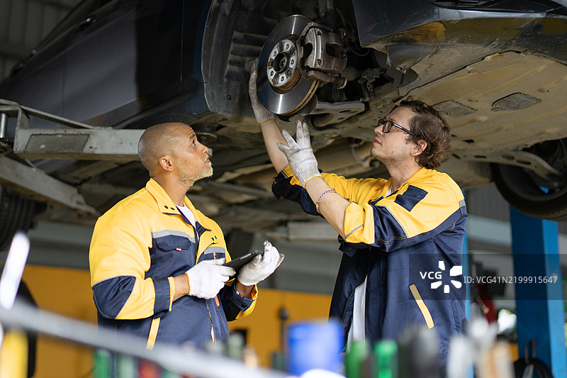 蓝领工人在汽车维修车间工作。图片素材