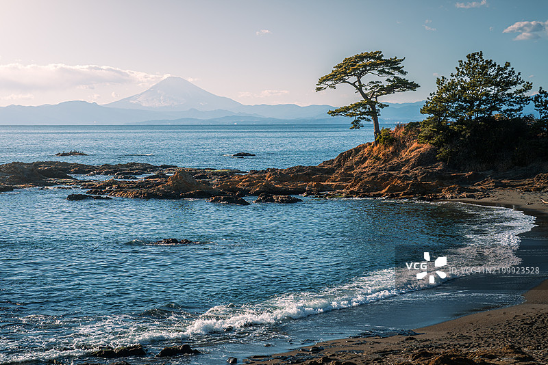 日本相模湾附近的雪山富士与一位站立的岩石渔民图片素材