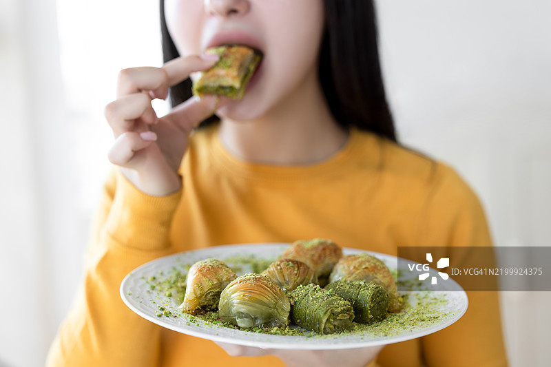 无法辨认的女性正在吃一盘巴克拉瓦。图片素材