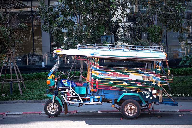 一辆色彩斑斓的改装摩托车和乘客车厢组成的嘟嘟车出租车停在老挝万象的路边。图片素材