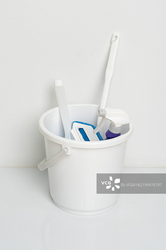 装有清洁用品的桶，背景为白色。塑料瓶中的清洁产品。家庭和办公室清洁的概念。家用化学品。图片素材