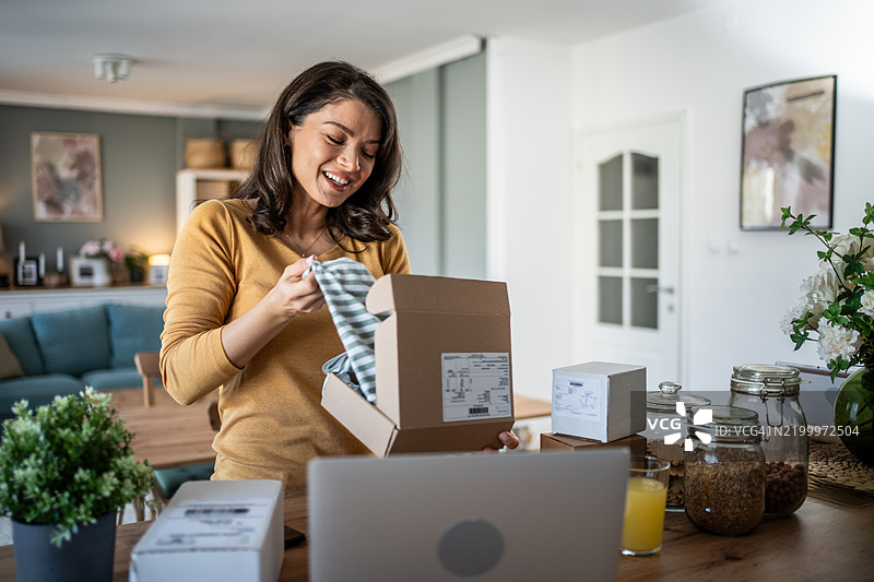 兴奋的年轻女性在家中打开包裹图片素材
