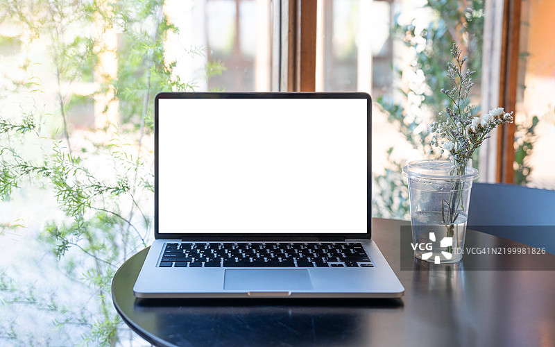 咖啡馆背景下桌子上的笔记本电脑空白屏幕。咖啡店桌子上的笔记本电脑空白屏幕，背景模糊。图片素材