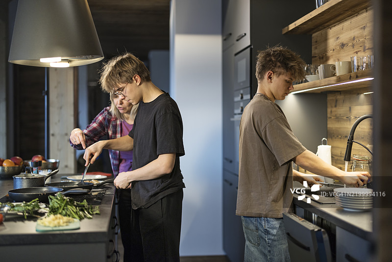 母亲和青少年男孩们正在准备托斯卡纳鸡肉餐。图片素材