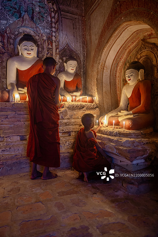 年轻僧侣在缅甸的蒲甘寺点燃蜡烛图片素材
