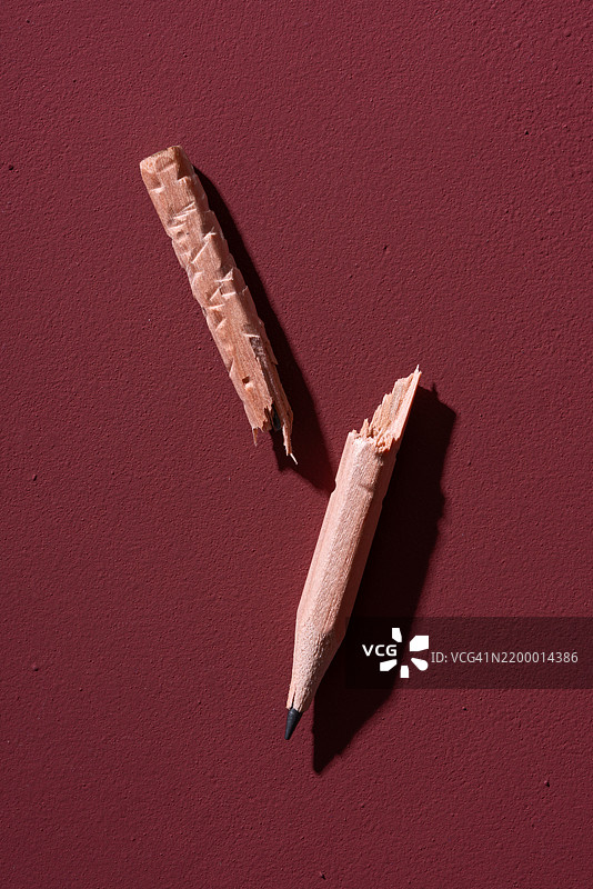 红色背景上的破损咬过的短铅笔图片素材