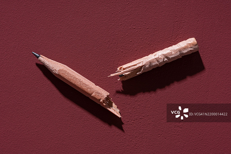 红色背景上的破损咬过的短铅笔图片素材
