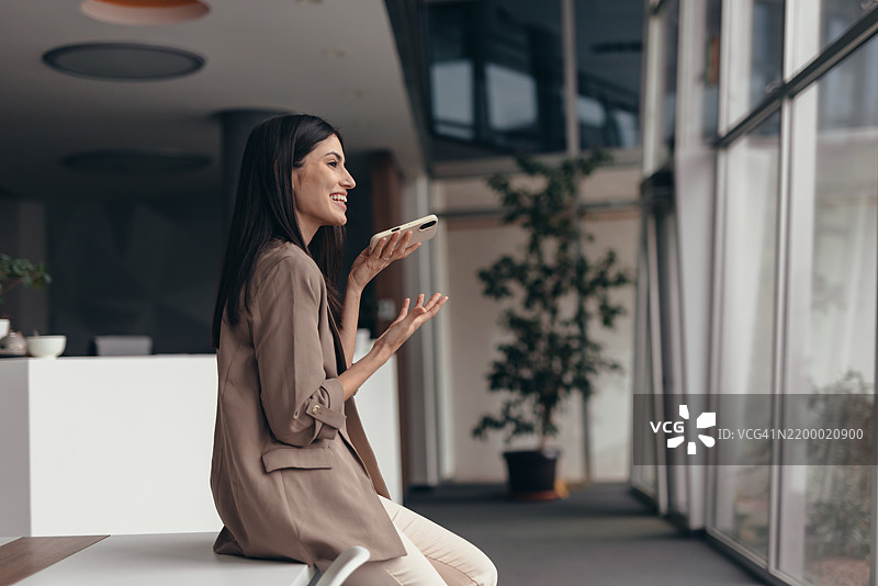 年轻女商人在现代办公室中使用免提电话交谈图片素材