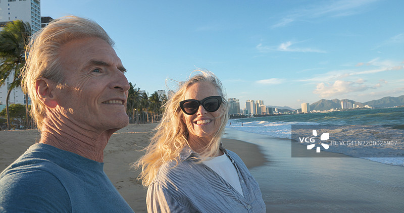 成熟夫妇在海滩上一起散步的侧面视图图片素材