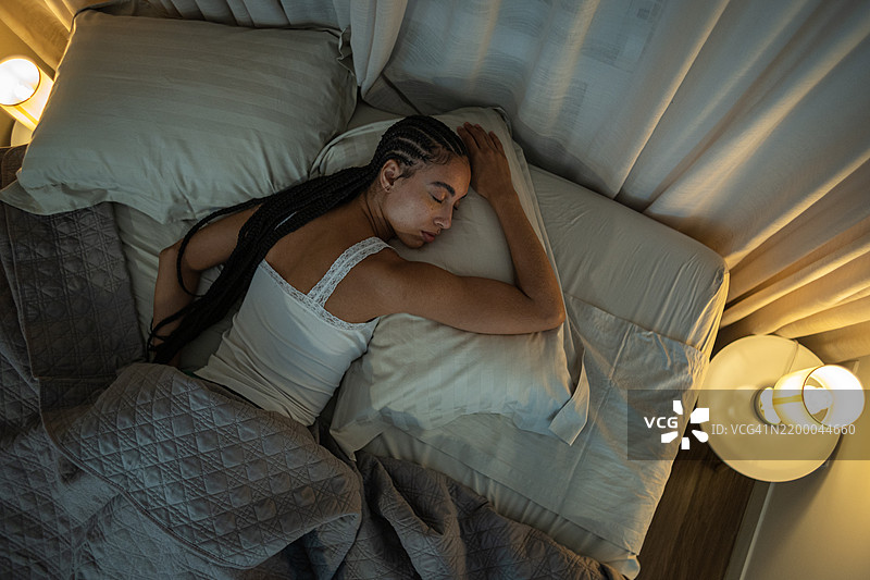 年轻女性舒适地躺在床上睡觉的俯视图图片素材