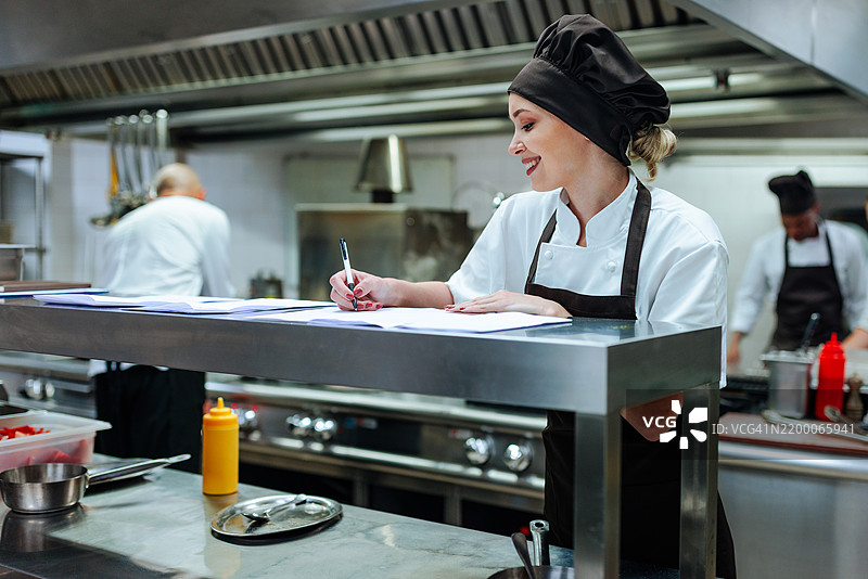 女厨师在餐厅厨房里写下笔记图片素材