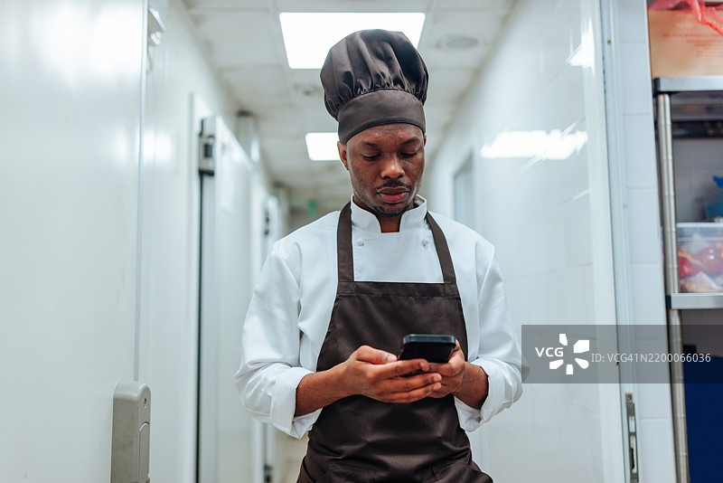 厨师在餐厅厨房走廊使用智能手机图片素材