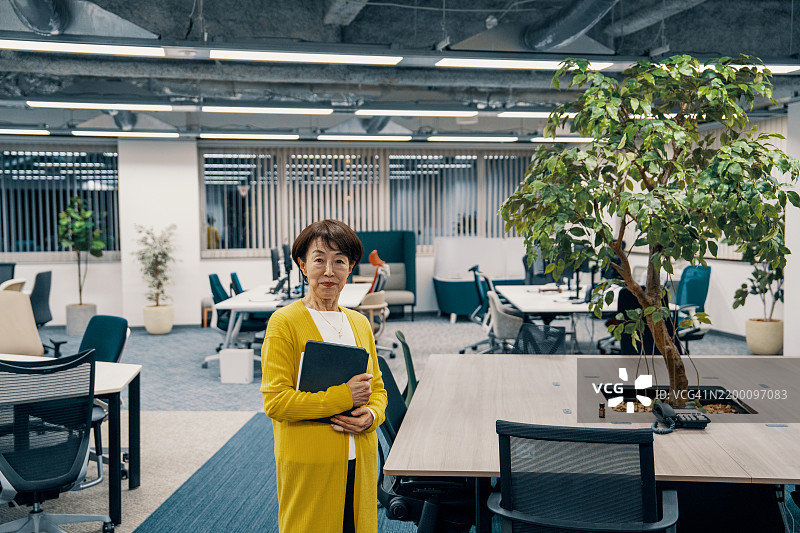 夜晚办公室里一位独自坐着的老年女性肖像图片素材