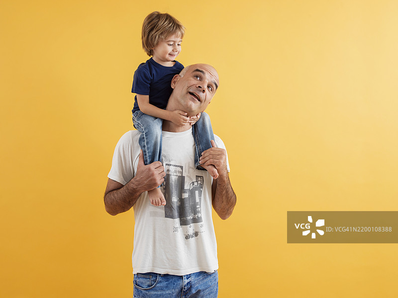父亲和孩子在明亮的黄色背景下玩得很开心图片素材