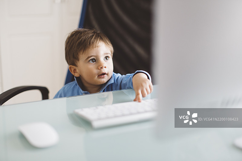 孩子好奇地坐在桌子前探索电脑图片素材