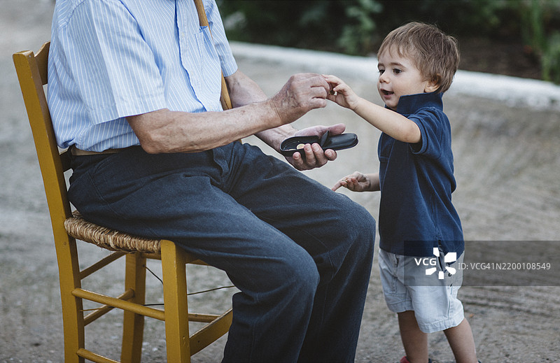孩子在阳光明媚的下午与长者在花园中互动图片素材
