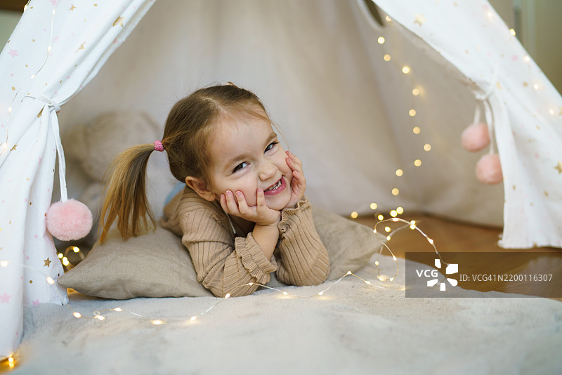 一个小女孩在家里的帐篷里躺着图片素材