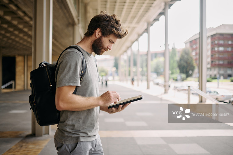 在机场户外，背着背包的男子正在使用应用程序检查住宿预订。冒险、数字科技和男性游客在城市中使用在线语言翻译进行探索。图片素材
