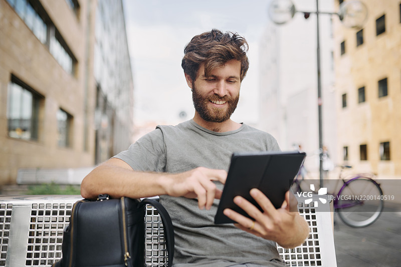 旅行，快乐的男子在城市中使用平板电脑查看住宿预订应用，背着背包。冒险，数字科技和游客在城镇中使用在线语言翻译进行探索。图片素材