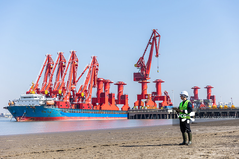 一名男性工程师在码头记录数据并指导工作图片素材