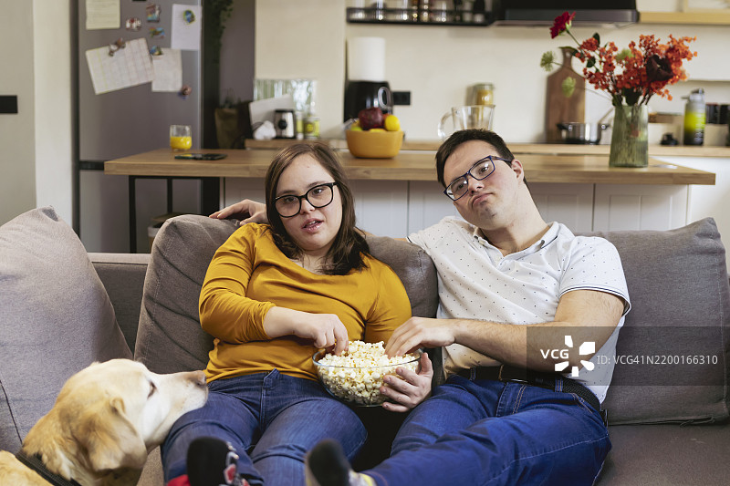 两位年轻的唐氏综合症人士正在吃爆米花并观看电影图片素材