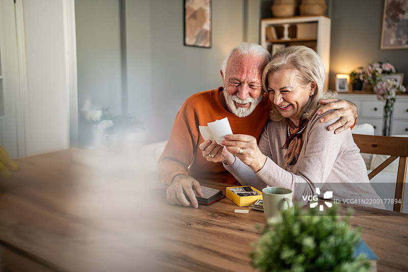 快乐的老年夫妇在怀旧的时刻中欣赏旧照片图片素材