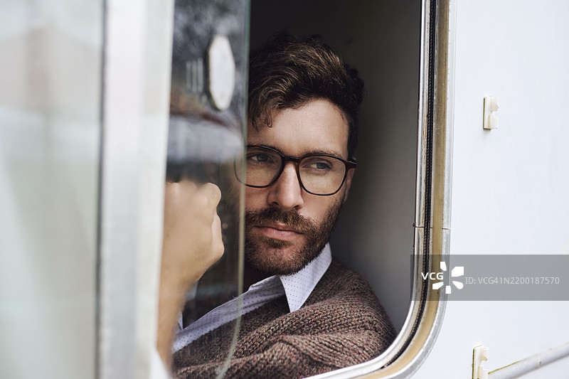 窗户，思考与旅行，男人在面包车中进行公路旅行，反思与冒险。离网，愿景与探索，佩戴眼镜的人在房车中度假，交通与记忆。图片素材