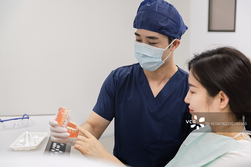 牙医向孩子展示牙齿模型。图片素材