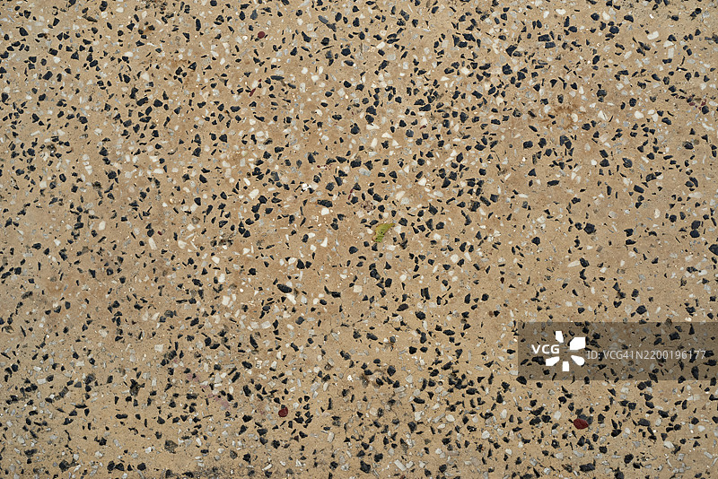 抛光石材表面显示出嵌入米色混凝土中的细小黑白卵石图片素材