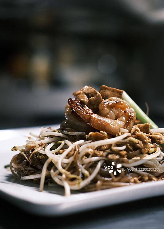 泰式炒河粉特写，配有炒虾、豆芽和米粉，盛放在白色盘子上，点缀新鲜青葱，正宗泰国街头美食，适合餐厅品牌和美食摄影。图片素材