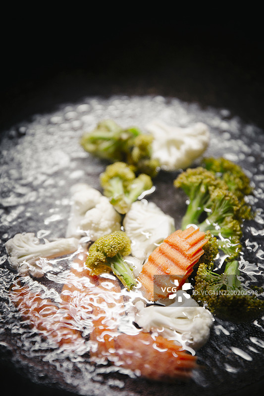 新鲜蔬菜特写，包括西兰花、花椰菜和胡萝卜，在热水中煮沸，餐厅环境中的泰国菜烹饪准备。图片素材