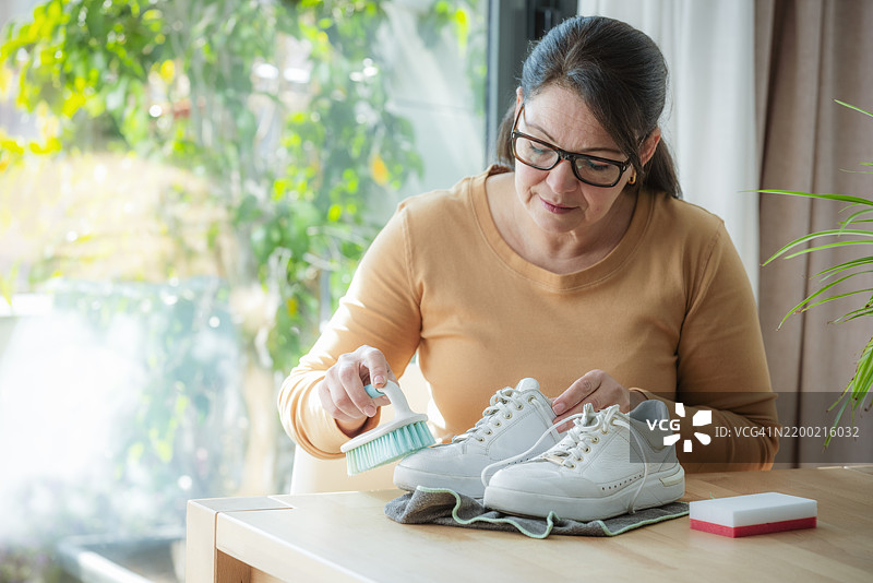 女人用刷子清洗她的白色运动鞋图片素材