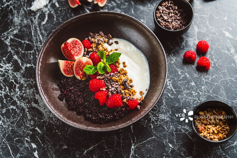 健康食品碗，包含黑米、酸奶、可可豆、燕麦片和新鲜水果图片素材