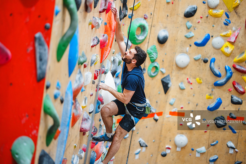 男子在室内攀岩墙上进行体育训练图片素材