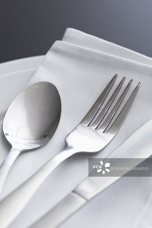 优雅的餐桌布置，配有银色餐具和鲜艳的布餐巾，为时尚的用餐体验增添魅力图片素材