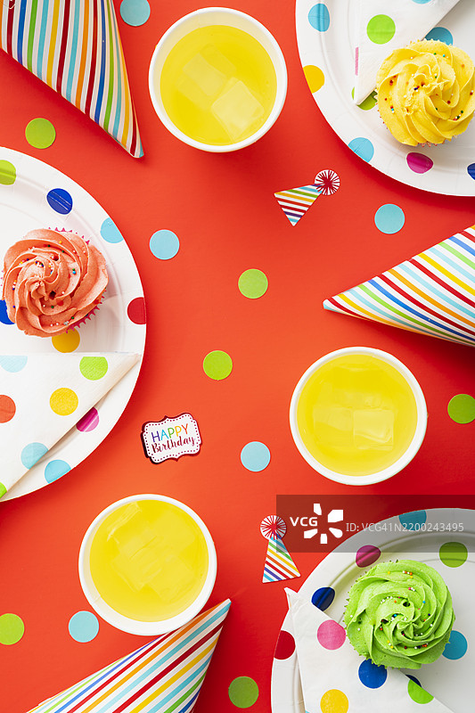 五彩缤纷的生日派对布置，桌布上摆放着杯子蛋糕和饮料。图片素材
