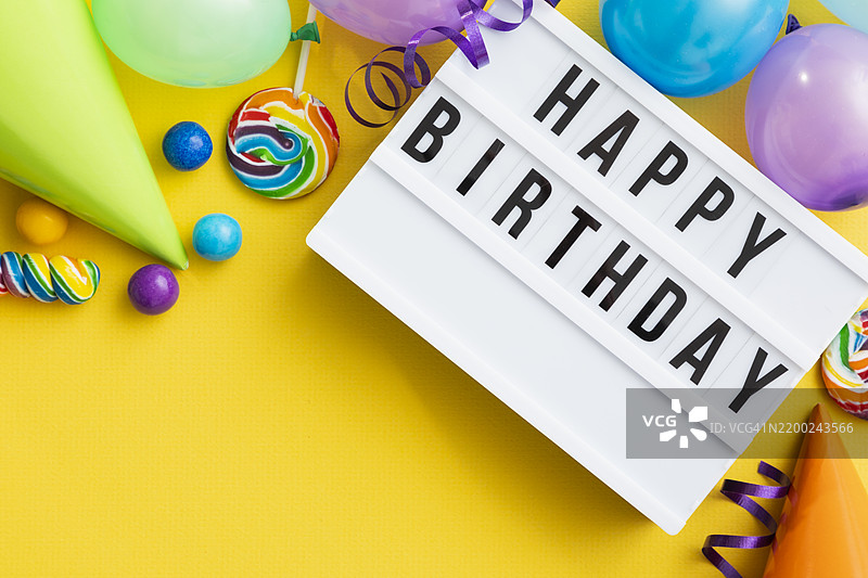 五彩缤纷的生日庆祝布置，装饰品、甜点和节日元素在鲜艳的黄色背景上。图片素材