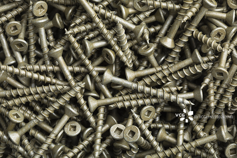 金属螺丝散落在工作坊环境中的表面上，阳光明媚。图片素材