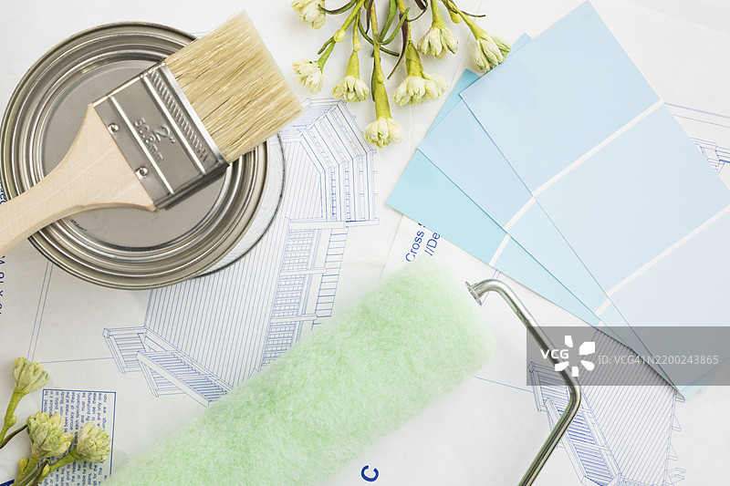 创意装修工具放在蓝图上，旁边有油漆样本和花卉装饰，适用于家庭改善项目图片素材