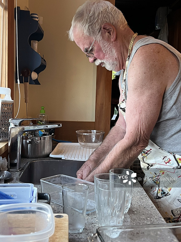 心烦意乱的活跃老年男子在厨房清洗碗碟图片素材