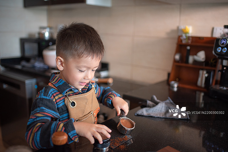 专注的孩子在现代厨房里准备咖啡图片素材
