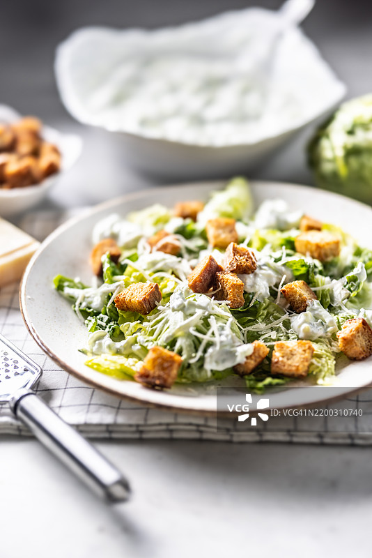 健康的凯撒沙拉，配有罗马生菜、面包丁、酸奶酱和帕尔马干酪。图片素材