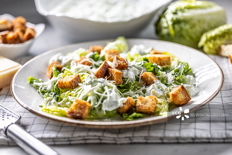 健康的凯撒沙拉，配有罗马生菜、面包丁、酸奶酱和帕尔马干酪。图片素材