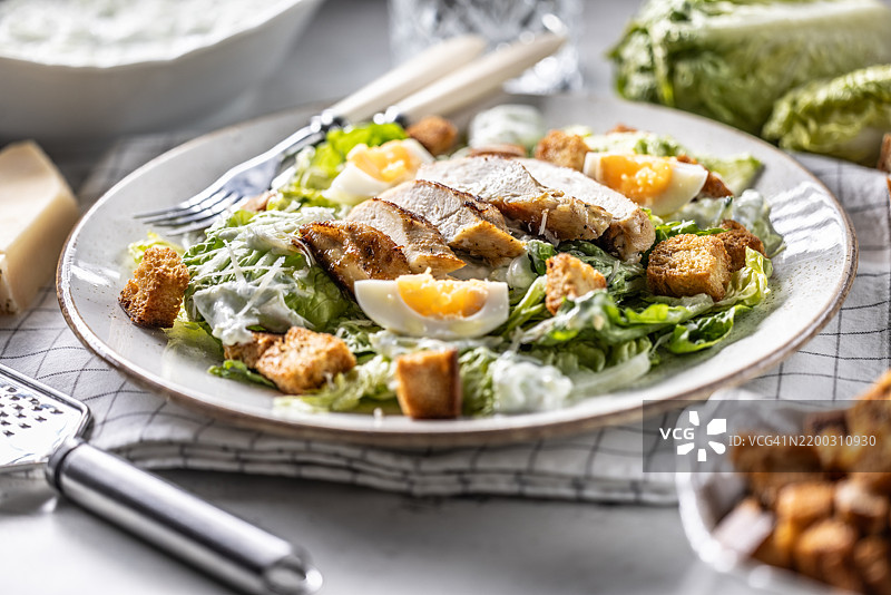 健康的凯撒沙拉，配有罗马生菜、烤鸡胸肉、鸡蛋、面包丁、酸奶酱和帕尔马干酪。图片素材